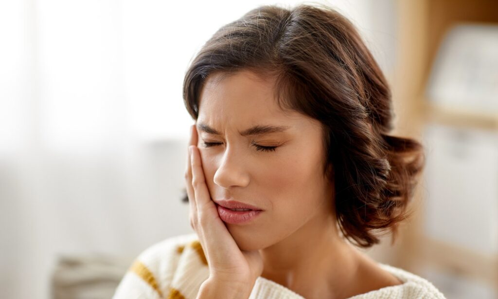 Woman experiencing tooth pain after cracking a tooth, considering emergency dental care in Buckeye, AZ